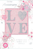 In this image, an anniversary card lies neatly displayed, its design a gentle celebration of lasting romance in tones reminiscent of a soft Pentonville evening. The main feature is the word LOVE, rendered in softly raised lettering coated with fine, shimmering glitter. Each letter appears in a blush-tinted white, edged with silver that sparkles delicately when touched by the light, giving the impression of a jewelled keepsake. Where the eye rests on the centre, the letter O subtly suggests the form of a heart, echoing the emotional heart of the occasion. Around this focal word, a cascade of delicate blooms flows outward, painted or printed in pastel pinks, mauves and gentle greys. The flowers have an almost watercolour softness, with edges that look lightly feathered, as if they've been brushed onto the card by hand. Curving vines, swirling flourishes and tiny petals create a feeling of gentle movement, as though a breeze were passing through an English spring garden tucked away behind the townhouses of Pentonville. Here and there, tiny butterflies and fine silver accents glint among the blooms, adding a note of whimsy. The background is a muted blush, calming and intimate, allowing the florals and central word to shine without overwhelming the senses. Elegant greetings such as On Our Anniversary and I love you today and always are written in a graceful script that complements the flowing floral lines. The card feels like a paper companion to a romantic bouquet delivered locally, a softly spoken, deeply heartfelt tribute to shared years and quiet promises kept.